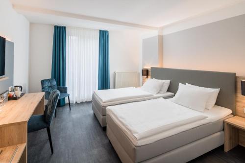 a hotel room with two beds and a desk at Best Western Hotel Lippstadt in Lippstadt