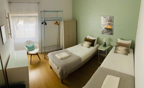 een kleine slaapkamer met 2 bedden en een stoel bij Feel Cascais Center 2bd in Cascais