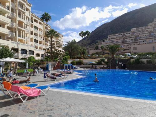 una piscina en un hotel con gente sentada en sillas en Castel Harbour Tenerife, en Los Cristianos