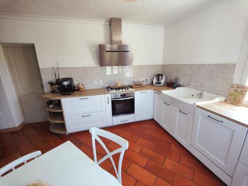 cocina con armarios blancos y suelo de baldosa roja en Superbe villa avec piscine, en LʼEscarène