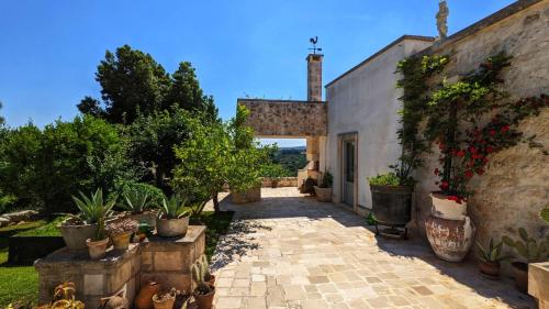 einen Außenweg mit Topfpflanzen und einem Gebäude in der Unterkunft Villa La Rona Masseria Trulli in Cisternino