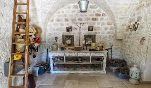Zimmer mit einer Steinmauer mit einem Tisch und einer Leiter in der Unterkunft Villa La Rona Masseria Trulli in Cisternino