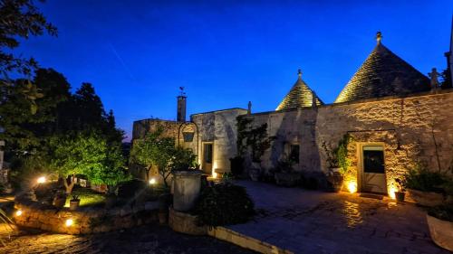 ein altes Steingebäude mit Lichtern in der Nacht in der Unterkunft Villa La Rona Masseria Trulli in Cisternino