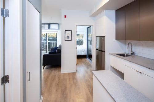 a kitchen with white cabinets and a black couch in a room at Micro Boutique Living Fredericton in Fredericton