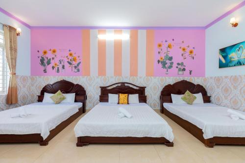 2 camas en una habitación con paredes rosas y moradas en Homestay Bảo Anh, en Vung Tau