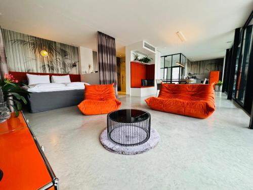 a living room with orange furniture and a bed at Orange Lounge in Weyregg