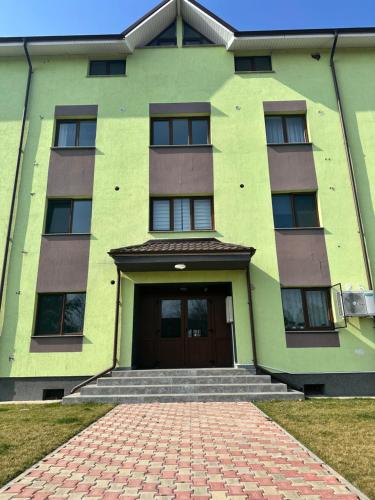 a green building with a door and a brick driveway at Apartament Natymar2 in Adjud