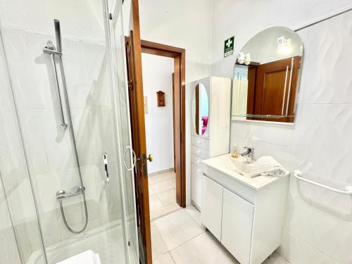 een witte badkamer met een douche en een wastafel bij Apartment Algarve - Beach Front - Free Wifi - Air Con in Armação de Pêra