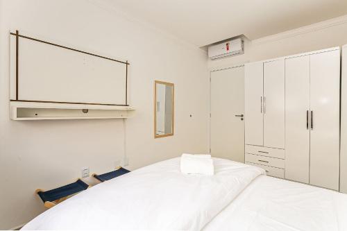 Apto c/ churrasq. e piscina - quadra mar - RMI201 في فلوريانوبوليس: غرفة نوم بيضاء مع سرير كبير وتلفزيون
