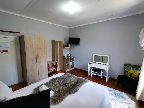 um quarto com uma cama branca e uma televisão em PLANES em Kokstad