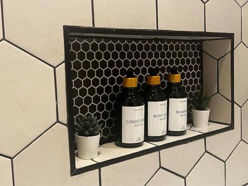 a shelf with four bottles of wine and potted plants at Charming Family Home with Gym in Henley on Thames