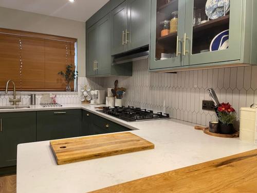 a kitchen with green cabinets and a wooden counter top at Charming Family Home with Gym in Henley on Thames