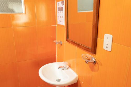 an orange bathroom with a sink and a mirror at Hotel Juanambu in Pasto