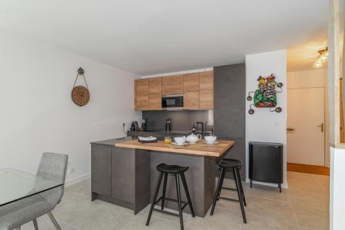 une cuisine avec un îlot et des tabourets. dans l'établissement Les Bergeronnettes - Piscine partagée proche plage, à Gujan-Mestras