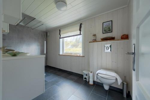 a bathroom with a toilet and a window at Cozy House By The Fjord In The Heart Of Lofoten in Reine