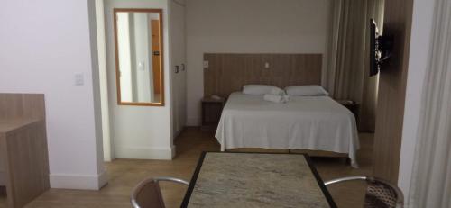 - une chambre avec un lit, une table et un miroir dans l'établissement Flat Suíte Superior, com acesso ao clube super quadra A, à Vitória