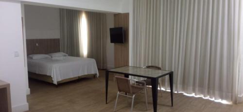 une chambre d'hôtel avec un lit, une table et des chaises dans l'établissement Flat Suíte Superior, com acesso ao clube super quadra A, à Vitória