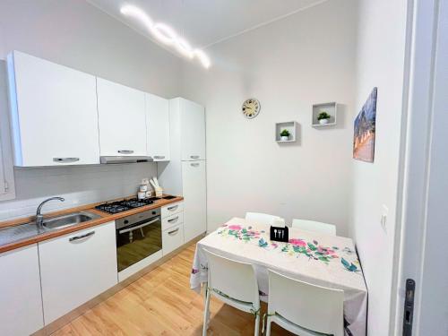 uma cozinha branca com uma mesa e um lavatório em Kenzia Apartment em Trapani