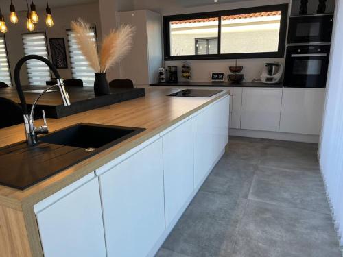 a kitchen with white cabinets and a wooden counter top at Villa accueillante à Millas avec piscine privée et jacuzzi in Millas