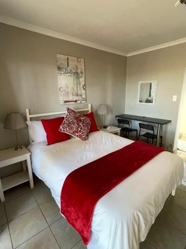 a bedroom with a large white bed with red pillows at Harmonie in Prieska