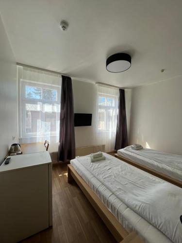 een kamer met 2 bedden, een wastafel en 2 ramen bij Elīna in Jūrmala