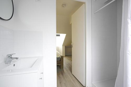 une salle de bain blanche avec un lavabo et un miroir dans l'établissement F2 hypercentre - Proche gare - WIFI gratuite, au Havre