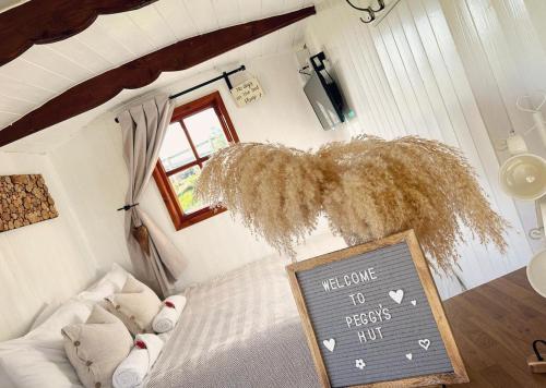 a bedroom with a chalkboard with a welcome to respects him sign at Peggy’s Hut in Astbury