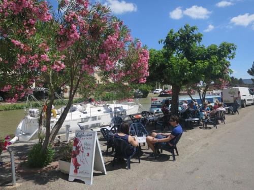 un groupe de personnes assises à des tables près d'un port de plaisance dans l'établissement Apartment Château de Jouarres-4 by Interhome, à Azille