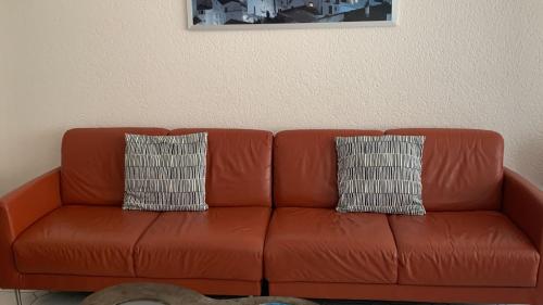 ein braunes Ledersofa mit zwei Kissen darauf in der Unterkunft Appartement 2 chambres spacieux pour 4 personnes in Knokke-Heist