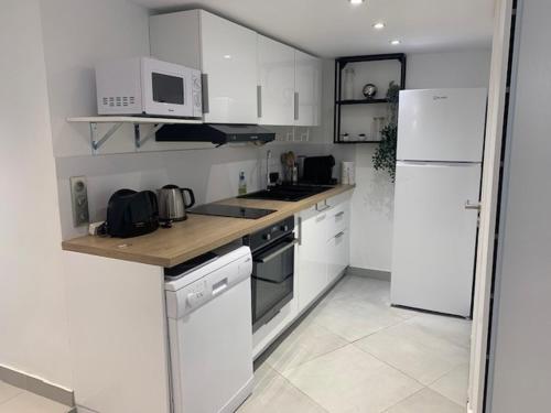 a kitchen with white cabinets and a white refrigerator at AUBERGE APPARTEMENT ORMESSON SUR MARNE / SUCY EN BRIE in Sucy-en-Brie