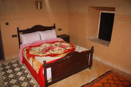 a bedroom with a bed with a red blanket and a window at La perle de saghro in Nkob