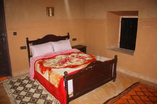 a bedroom with a bed with a red and white blanket at La perle de saghro in Nkob