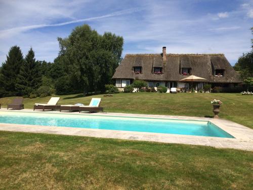 une maison avec une piscine devant une maison dans l'établissement grande Chaumière avec piscine chauffée Normandie, à Vieux-Bourg