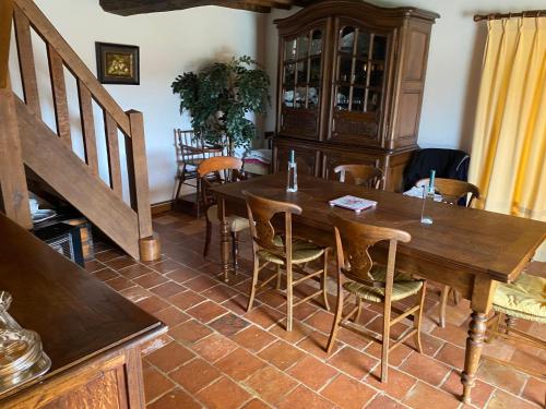une salle à manger avec une table et des chaises en bois dans l'établissement grande Chaumière avec piscine chauffée Normandie, à Vieux-Bourg