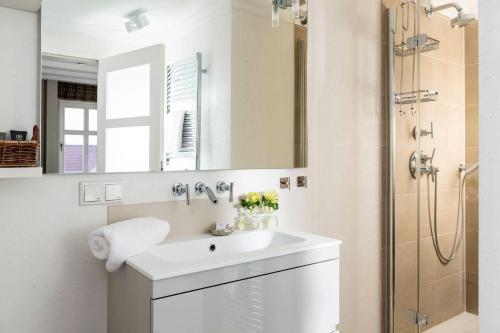La salle de bains blanche est pourvue d'un lavabo et d'une douche. dans l'établissement Strandvilla-504, à Westerland