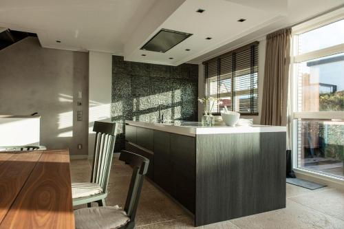 a kitchen with a island with chairs and a table at Strandhaus-Ocean in Hörnum