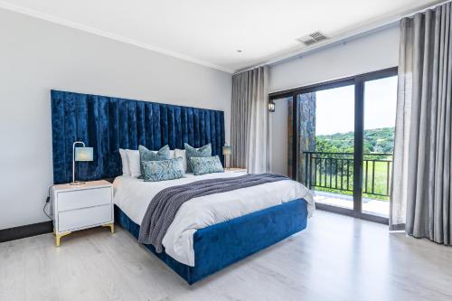 ein Schlafzimmer mit einem großen Bett und einem großen Fenster in der Unterkunft Baluwatu 10, Zimbali Estate in Ballito