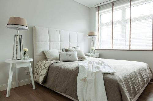 a white bedroom with a bed and a window at Strandhaus-Shell in Hörnum