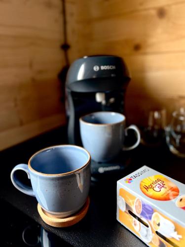 two cups on a counter next to a coffee maker at Górna Kudowa Domki Wypoczynkowe z balią in Kudowa-Zdrój
