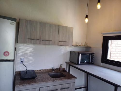 Una cocina con un fregadero y un microondas en una encimera. en Alojamiento San Juan, en Trinidad