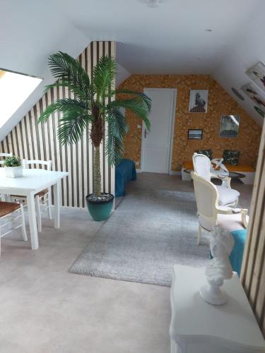 - un salon avec un palmier, une table et des chaises dans l'établissement Les Suites de Véronique, chez Véronique Olive, à Saint-Pair-sur-Mer