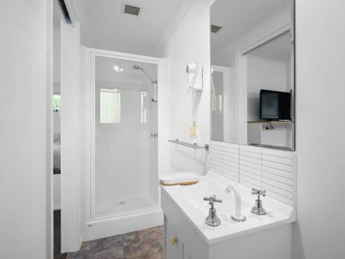 uma casa de banho branca com um lavatório e um chuveiro em Kalisti Suites - Fira Suite em Port Sorell