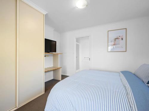 um quarto branco com uma cama e uma televisão em Kalisti Suites - Fira Suite em Port Sorell