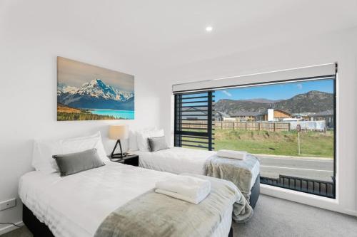a bedroom with two beds and a large window at Clutha River Haven in Albert Town
