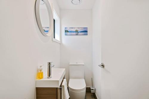 a bathroom with a white toilet and a sink at Clutha River Haven in Albert Town