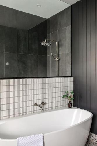 a bathroom with a white tub and black tiles at Mulgrave Street Cottage- renovated comfort in Kings Park