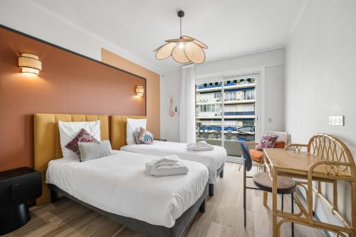 une chambre d'hôtel avec deux lits et une table dans l'établissement Jessicannes - COOPER - 3 chambres - Central, spacieux, terrasse, à Cannes