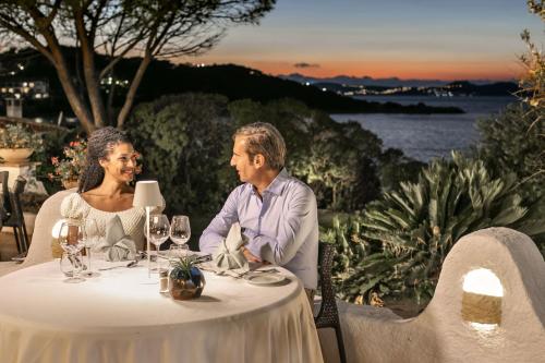 a man and a woman sitting at a table at Hotel La Bisaccia in Baja Sardinia