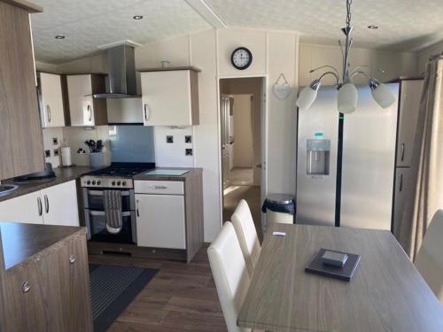 a kitchen with a table and a kitchen with a refrigerator at 2 Bed, 2 Bath Lodge Style Caravan with Hot Tub & Private Garden in Patrington
