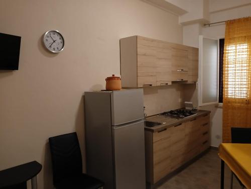 a kitchen with a refrigerator and a clock on the wall at Casa Trio Appartamento 1 piano con balcone e Appartamentino su due livelli con terrazza in Castellammare del Golfo